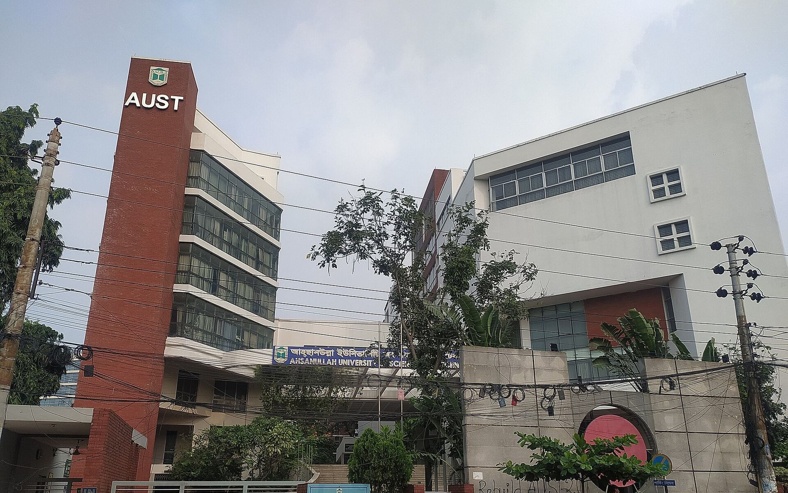 The red brick tower and white academic building of Ahsanullah University of Science and Technology in Tejgaon, Dhaka, seen from the street