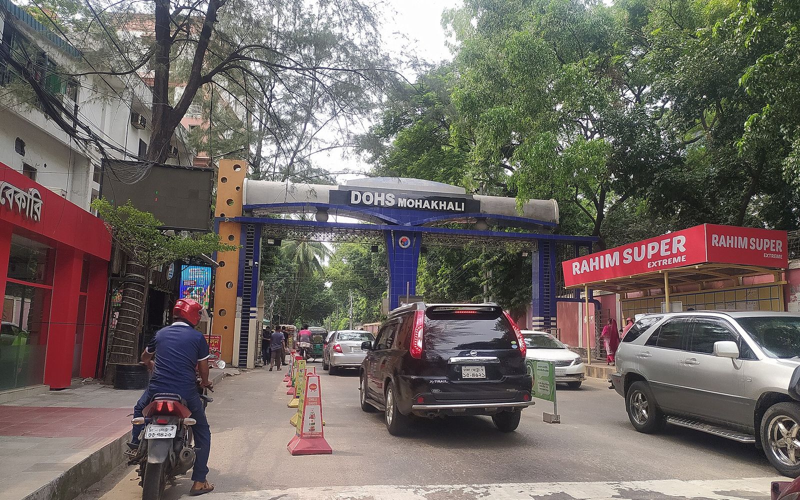 BAT Global Graduate Programme in Bangladesh: What Is Published and What Is Not 1 The CV Guy is the No.1 Resume/CV Writer in Bangladesh, Asia & Middle East Cars and a motorcyclist at the blue entrance gate of Mohakhali DOHS in Dhaka, under trees