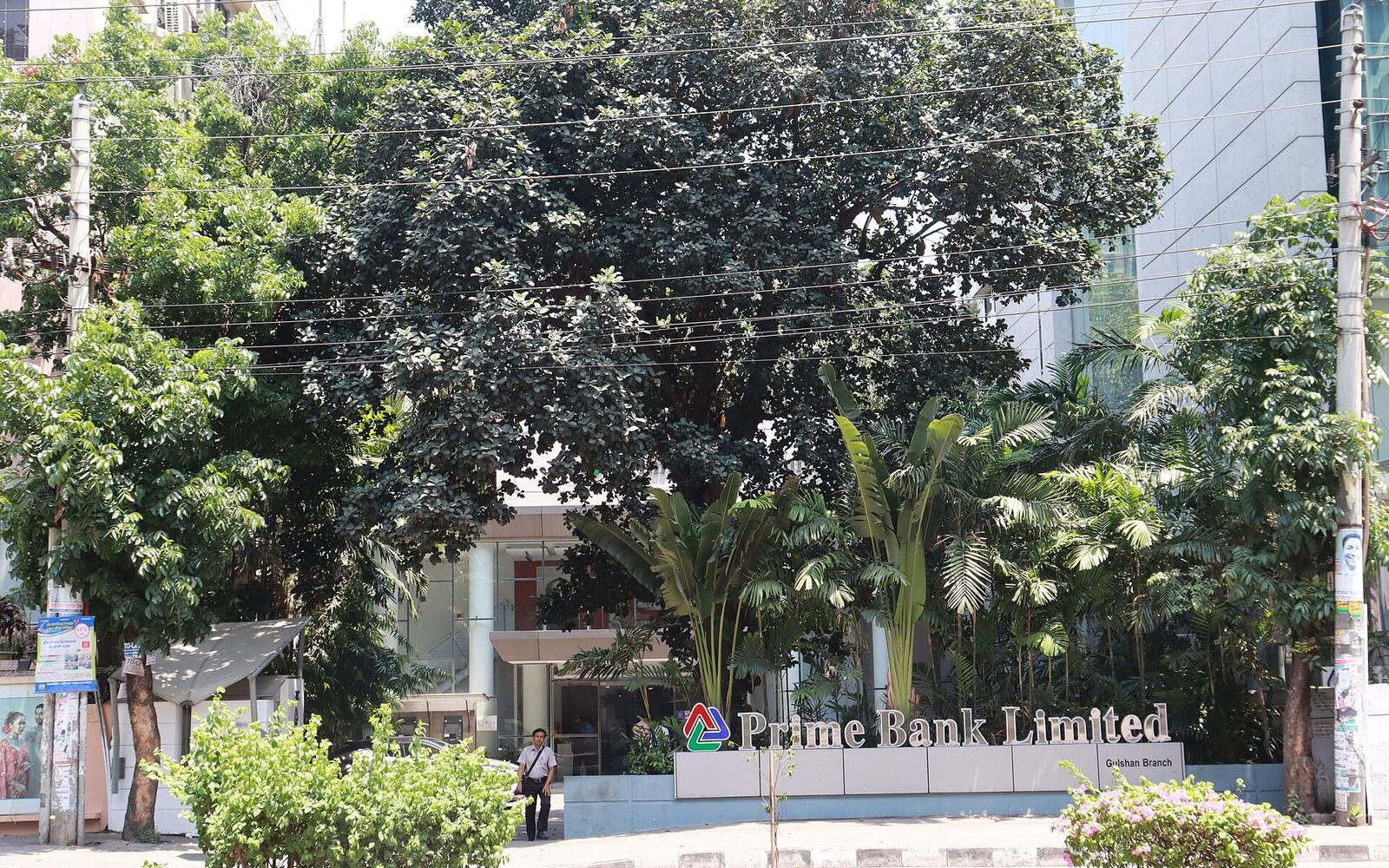 Prime Bank Limited Gulshan Branch in Dhaka, with its sign in front of a glass entrance behind large trees