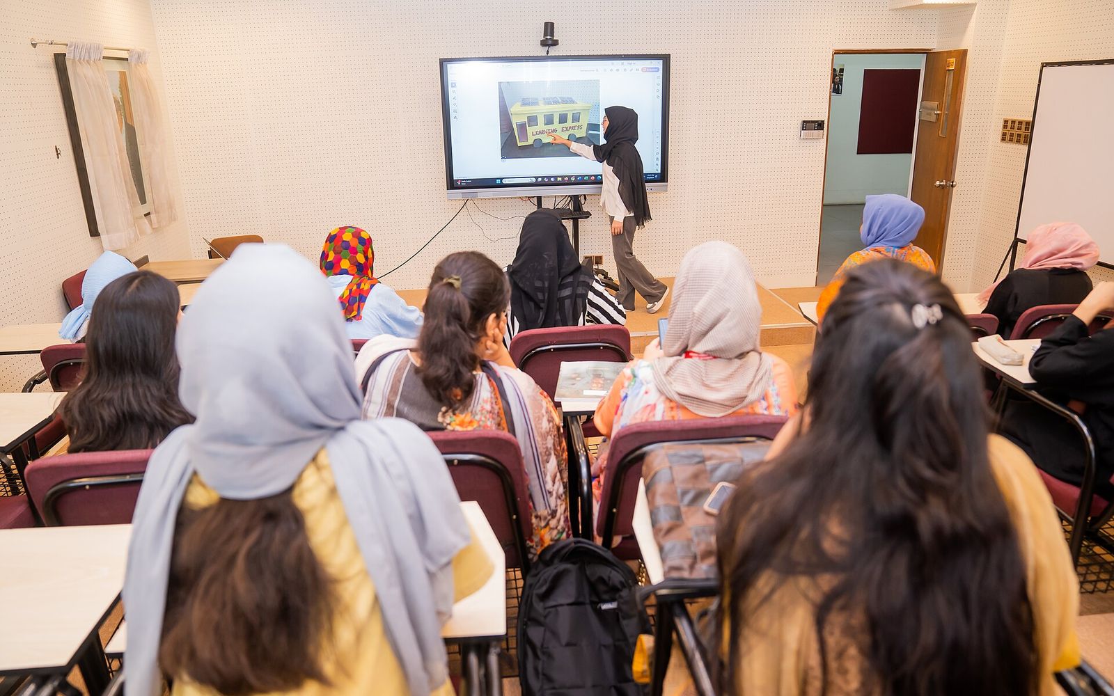 FGD Preparation for MNC Jobs in Bangladesh: What Employers and Recruits Have Put on Record 2 The CV Guy is the No.1 Resume/CV Writer in Bangladesh, Asia & Middle East Students seen from behind in a classroom in Bangladesh watching a classmate present a project on a wall screen